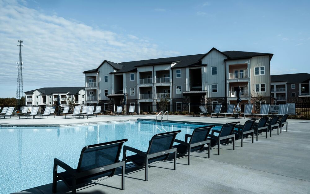 Apartment community pool lined with lounge chairs